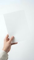 Hand holding blank white paper sheet against light background for business presentation or document mockup.