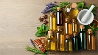 Essential oils collection with herbs and spices on wooden background. Natural aromatherapy bottles with lavender, rosemary, mint for wellness and spa treatments.