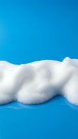 White fluffy foam bubbles on bright blue background for cleaning products advertising and hygiene concept designs.