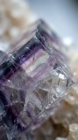 Purple fluorite crystal with geometric cubic structure and natural inclusions on blurred mineral background for geology education and gemstone collection.