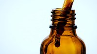 Amber glass dropper bottle with golden liquid pouring inside, isolated on white background for cosmetics, essential oils, serums, and skincare product packaging design.