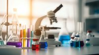 Modern laboratory workspace with microscope and colorful chemical solutions in glass beakers for scientific research and experimentation.