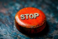 Red vintage metal button with stop text on dark textured background, dramatic lighting creates moody atmosphere for emergency and warning concepts.