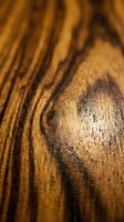 Close-up of natural wood grain texture with warm golden-brown tones and organic striped patterns, suitable for backgrounds, design elements, and woodworking projects.
