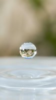 Clear crystal sphere floating above water surface with natural bokeh background creating serene meditation and mindfulness atmosphere for wellness concepts.