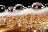 Macro shot of fizzy drink bubbles in golden liquid with white foam creating dynamic texture and pattern. Perfect for beverage advertising and design projects.