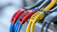 Colorful network patch cables with strain relief boots in red, blue, and yellow colors showing close-up detail of ethernet connections in data center environment.