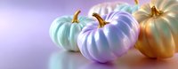 Pastel colored decorative pumpkins in mint, lavender and gold tones arranged on reflective surface against soft purple background. Modern autumn decor.