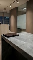 Modern office interior with leather portfolio on marble desk featuring contemporary lighting and wood paneling for corporate business presentations.