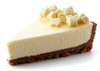 Slice of creamy white cheesecake with chocolate cookie crust and white chocolate chunks on top against white background, isolated dessert for menu or packaging design.