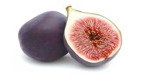 Fresh ripe purple fig fruit cut in half showing juicy pink flesh and seeds on white background, isolated food photography for healthy eating concepts.