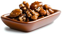 Caramelized walnuts in brown ceramic bowl on white background. Glazed nuts with honey coating for healthy snacking or gourmet dessert topping.
