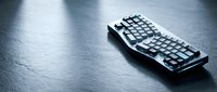 Ergonomic mechanical keyboard with curved design on dark textured surface, suitable for gaming, programming, and office work setups.