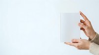 Caucasian woman with manicured nails holding blank white card or paper against neutral background for mockup, branding, advertising, and marketing presentations.