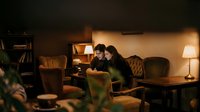 Young couple studying together with laptop in cozy evening library setting with warm lighting and comfortable seating area for academic research.