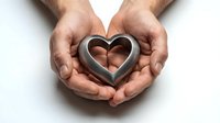 Male hands gently holding metallic heart shape symbol on white background, representing love, care, protection and emotional support concepts.