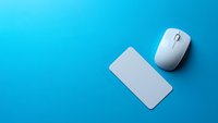 White wireless computer mouse and blank business card on vibrant blue background with dramatic lighting and copy space for technology mockup.
