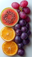 Fresh cut watermelon, orange halves and purple grapes arranged on white background. Vibrant summer fruits with water drops showing juicy, natural freshness.