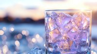 Refreshing drink with ice cubes in glass against blurred bokeh background at sunset. Sparkling beverage with melting ice creates atmospheric mood for summer cocktails.