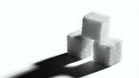 Stacked white sugar cubes casting dark shadows on isolated white background, suitable for nutrition, health, diet and food industry design projects.