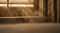 Warm golden sunlight streaming through window creating dust particles floating in air with soft bokeh background for cozy interior design concepts.