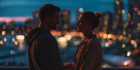 Young couple enjoying romantic evening together with city lights bokeh background creating intimate atmosphere for dating and relationships.