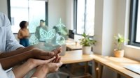 Professional hands holding glowing green eco-friendly icons in modern office workspace promoting sustainable business practices and environmental responsibility.