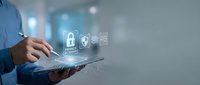 Businessman holding tablet with security icons including padlock and shield symbols, representing cybersecurity, data protection, and digital safety solutions for enterprise networks.