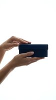 Female hands holding small dark blue gift box isolated on white background for product presentation and commercial use.