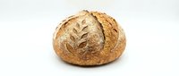 Artisan sourdough bread loaf with decorative wheat pattern scoring on crusty golden brown surface, isolated on white background for bakery designs.