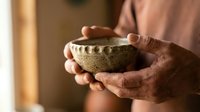 Hands holding handmade ceramic bowl with natural texture and earthy tones for mindful living and artisan crafts.