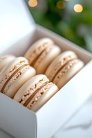Delicate vanilla macarons with golden sprinkles in white gift box against soft bokeh background. Close-up view shows creamy filling and detailed texture of French pastries.