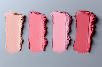 Pink lipstick or cream blush smear samples showing color gradient from light to dark on gray background, cosmetic texture swatches for beauty products.