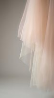 Elegant bridal veil with soft flowing layers in warm peachy pink tones against neutral background for wedding photography and romantic ceremonies.