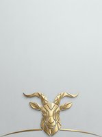 Geometric golden goat head with curved horns on white background, isolated design element suitable for logos, branding, and creative projects.