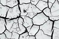 Cracked dry earth texture with deep fissures forming abstract natural pattern in black and white. Drought concept showing environmental impact.
