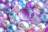 Luminous pearls and glass beads in pastel pink, purple, and turquoise colors create elegant jewelry background with soft focus and dreamy bokeh effect.