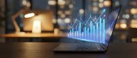 Laptop displaying glowing blue financial growth chart with upward trending arrow on wooden desk in modern office environment for business analytics presentations.