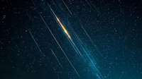 Spectacular meteor shower with bright falling stars streaking across dark night sky, glowing trails creating dramatic celestial light show against starry background.