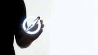 Silhouette of hand holding glowing power button symbol against bright light background representing technology startup and digital innovation concepts.
