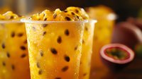 Fresh passion fruit mousse with black seeds in transparent glass, tropical dessert with smooth creamy texture and vibrant yellow color. Sweet summer treat.