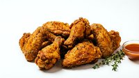Crispy fried chicken pieces with golden-brown coating, fresh thyme garnish, and sauce on white background for food advertising and restaurant menus.