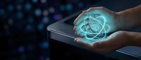 Hands holding smartphone with glowing atomic structure hologram emerging from screen representing nuclear science technology and digital innovation concepts.