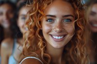 Young woman with curly red hair, freckles and bright blue eyes smiling at camera in crowd. Natural beauty portrait for lifestyle advertising.