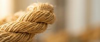 Close-up of natural jute rope with twisted fibers showing detailed texture and warm lighting for craft and nautical projects.