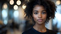 Young African American woman with natural curly hair in professional setting with warm bokeh lights background for business and lifestyle concepts.