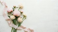 Soft pink and cream peonies bouquet with silk ribbon on white wooden background, copy space for wedding or romantic design.