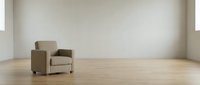 Modern beige armchair in minimalist empty room with wooden floor and white walls. Contemporary furniture piece for interior design and home decor concepts.