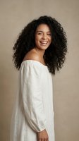Happy young African American woman with curly hair wearing white off-shoulder top smiling joyfully against neutral beige background for lifestyle content.