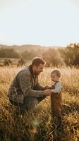 Loving father and toddler son bonding in golden wheat field during warm sunset light creating tender family moment in rural countryside setting.
